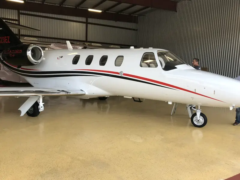 White private jet with tinted windows inside a hangar
