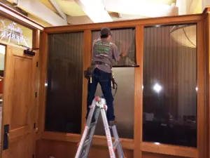 Mr. Tint installer applying film to a home’s wood-framed windows