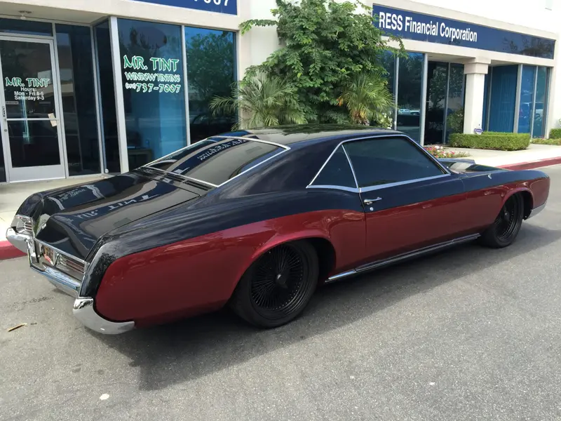 Classic red and black Buick Riviera with tinted windows